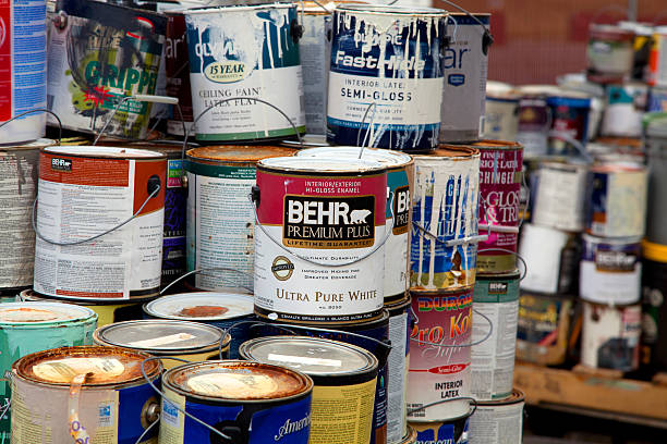 Used paint tins with manufacturer labels visible, collected for recycling and proper disposal.